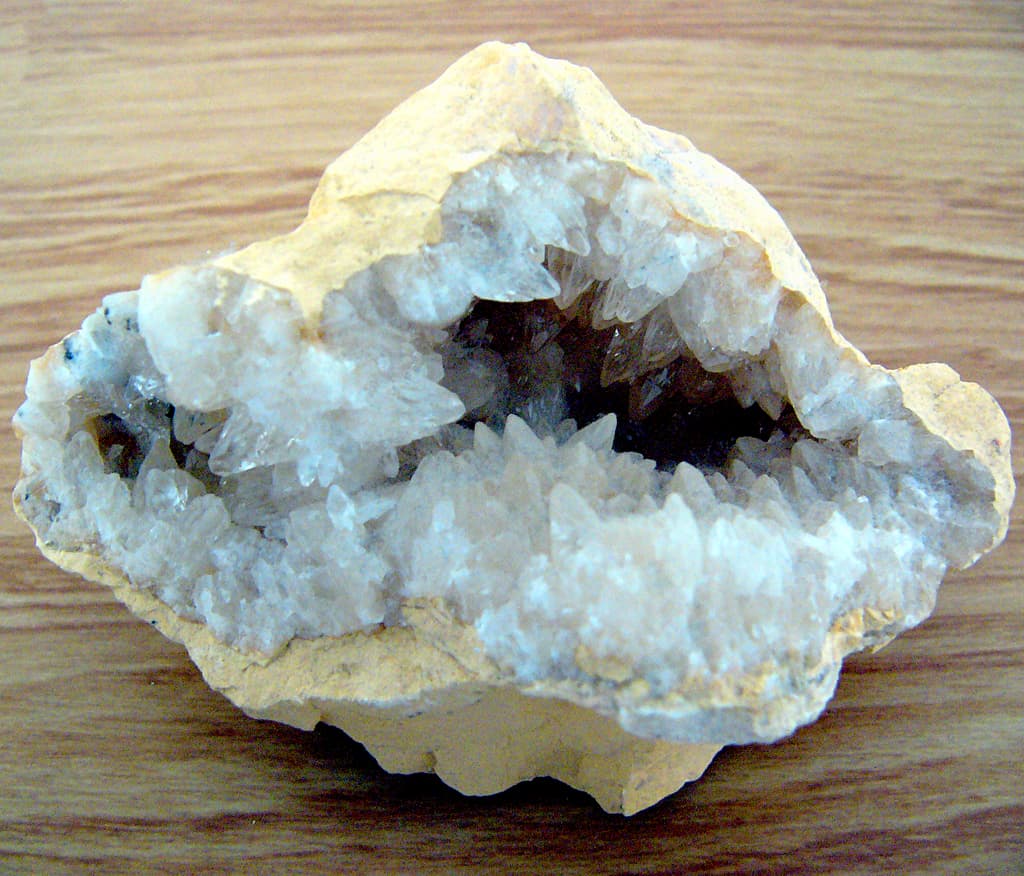 A geode split open to reveal a hollow cavity lined with sparkling quartz crystals