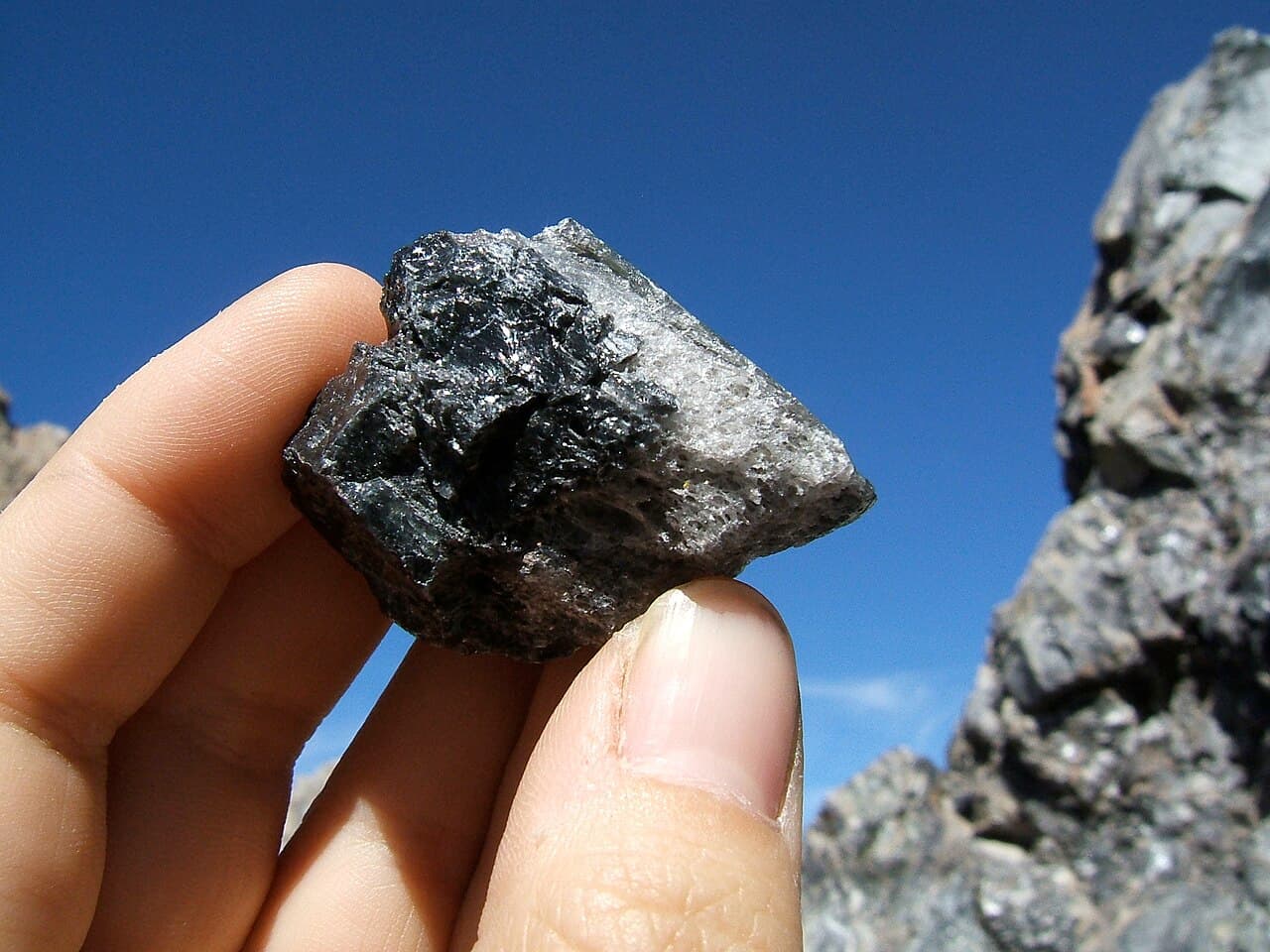Close-up of a glassy black obsidian rock, an example of an igneous rock formed from rapidly cooled lava