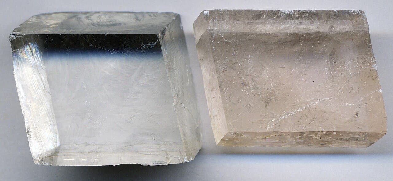 Broken calcite fragments showing perfect rhombohedral cleavage with flat, slanted faces